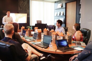 Trainer präsentiert in einem Büro einen Inhalt vor einer Gruppe von Schülern