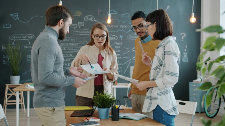 Business-Team prüft Druckmuster und bewertet Print-on-Demand Anbieter für Unternehmensdruck