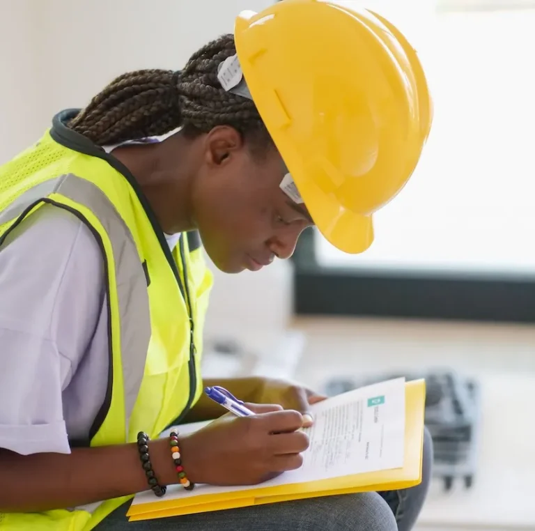 Mitarbeiterin in Schutzausrüstung füllt Schulungsunterlagen für Arbeitssicherheit aus